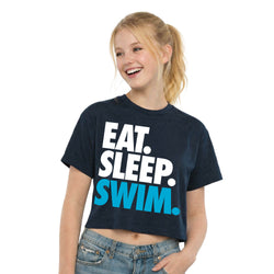Young girl wearing a navy t-shirt with 'EAT. SLEEP. SWIM.' text on a white background