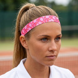Woman wearing a pink headband with tennis racket design on a tennis court