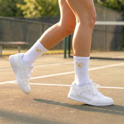 White sneakers and socks with a yellow tennis logo on a tennis court