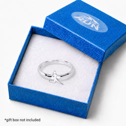 A silver ring with a small running figure charm, presented inside an open textured blue gift box with a white insert. The box lid has a circular logo, and a text overlay at the bottom left reads '*gift box not included'.