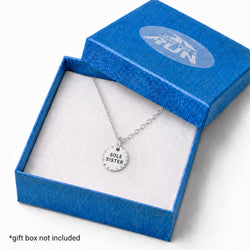A silver pendant necklace with the engraved words 'SOLE SISTER.' displayed inside an open textured blue gift box with a white insert.