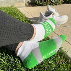 Person wearing green and white socks with motivational text, standing on grass.