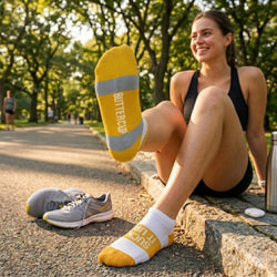 Woman sitting outdoors wearing yellow and white socks with Suck It Up, Buttercup text.