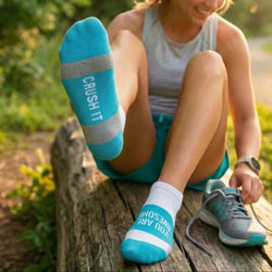 Woman sitting outdoors wearing socks with You Are Awesome, Crush It Text and running shoes.