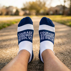 White socks with blue stripes and motivational text on a blurred outdoor background