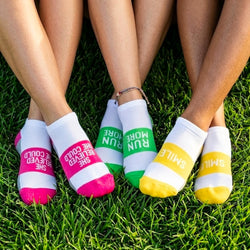 Three pairs of colorful socks with text on a grass background