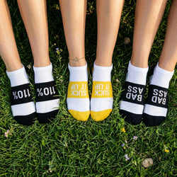 Three pairs of motivational socks with text on grass