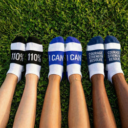 Three pairs of socks with motivational text on a grass background