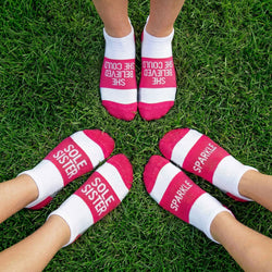 Pink and white motivational socks with text on grass