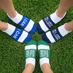 Three pairs of socks with motivational text on a grass background