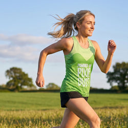 Woman running outdoors in a green tank top with text