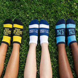Three pairs of socks with motivational text on grass