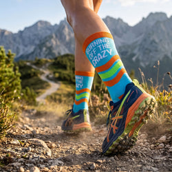 Person hiking on a trail with colorful socks and shoes, mountains in the background
