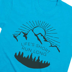 A close-up of a bright turquoise blue t-shirt featuring a black graphic print of mountains, a rising sun, and pine trees with the text 'LIFE'S SHORT RUN LONG'.