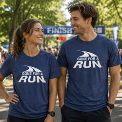 A man and a woman standing outdoors at what appears to be a race finish line, both wearing matching navy blue t-shirts with a white 'GONE FOR A RUN' graphic on the chest.