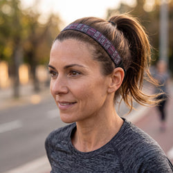 Woman wearing a headband with text, standing outdoors on a street.
