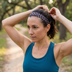 Woman adjusting a wine patterned headband outdoors on a nature path