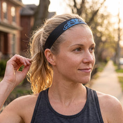 Woman adjusting a headband outdoors with blurred background