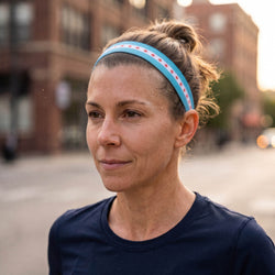 Woman wearing a blue headband with red and white stripes on a city street.