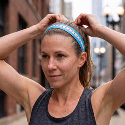 Woman adjusting a blue headband with red and white stars outdoors.
