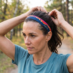 Woman adjusting a colorful headband outdoors in a natural setting
