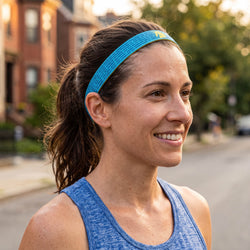 Woman wearing a blue Boston headband and green tank top on a city street.