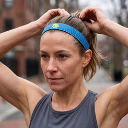 Woman adjusting a blue Boston headband outdoors
