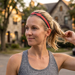 Woman adjusting a red and black headband with a blurred background