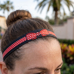 Person wearing a red and white polka dot headband with a blurred outdoor background