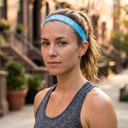 Woman wearing a blue tank top and headband with 'Eat my pixie dust' text, outdoors.