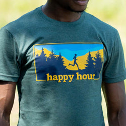 A close-up of a person wearing a dark green heathered t-shirt with a graphic print on the chest. The graphic features a yellow and blue landscape with a silhouette of a runner and the text 'happy hour'.