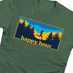 A close-up of a heather green t-shirt featuring a rectangular graphic print on the chest. The graphic shows a runner silhouette against a mountain landscape with blue sky, yellow mountains, and dark blue trees, with the text 'happy hour' in yellow.