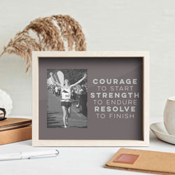 Framed print with a black and white photo of a runner and motivational text on a desk.