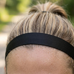 Close-up of a person wearing a black headband with a blurred natural background