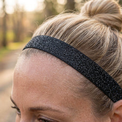 Person wearing a black glittery headband outdoors with a blurred natural background