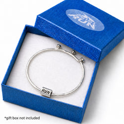 A silver bangle bracelet with a rectangular charm engraved with 'RUN', displayed inside an open blue gift box with a white insert. The box lid has a translucent 'GONE FOR A RUN' logo.