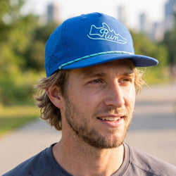 Man wearing a blue cap with a run shoe logo outdoors