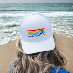 Person wearing a cap with 'run like a girl' design on a beach