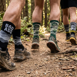 People hiking on a trail wearing colorful socks with visible text and patterns.