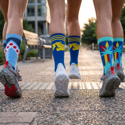 Three pairs of legs wearing colorful running socks on a paved path.