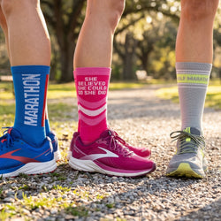 Three pairs of running shoes with colorful socks on a gravel path.