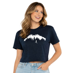 Woman wearing a navy blue t-shirt with a mountain and person graphic on a white background