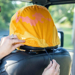 Person adjusting a yellow seat cover with pink patterns on a car seat.