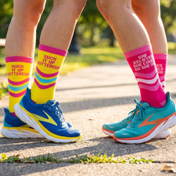Two pairs of colorful socks and running shoes on a road.