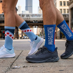 Two pairs of legs wearing colorful marathon socks with a cityscape background