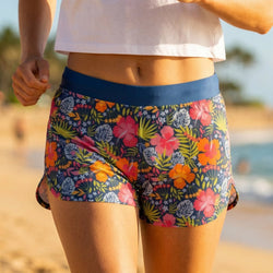 Person wearing colorful floral shorts on a beach