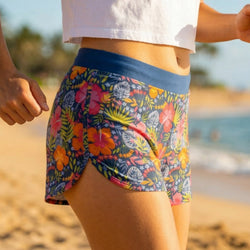 Person wearing colorful floral shorts on a beach