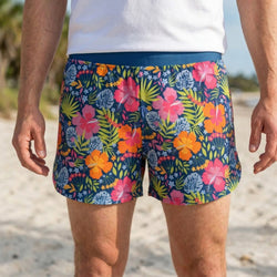 Person wearing colorful floral shorts on a beach.