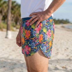 Person wearing colorful floral shorts on a beach