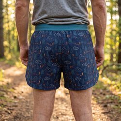 Person wearing blue patterned shorts in a forest setting